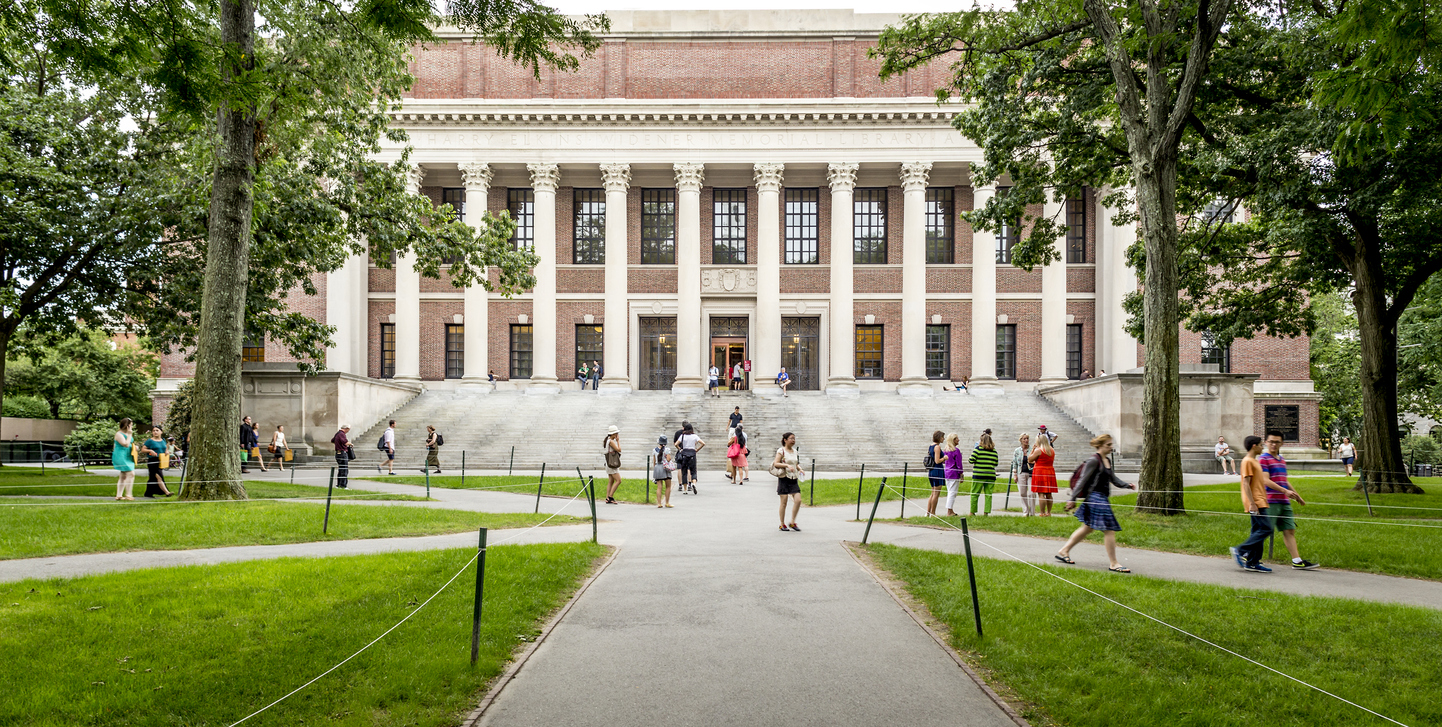 Cambridge, MA, USA - October 10, 2017: View of the iconic architecture of the Harvard University in Cambridge, MA, USA with some locals, tourists, and students passing by.