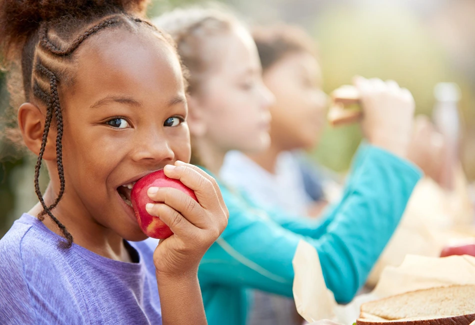 Sack Lunches - girl eating an apple. Photo credit Freepik